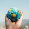 Hand holding a globe against a mountain background symbolizing travel and exploration.